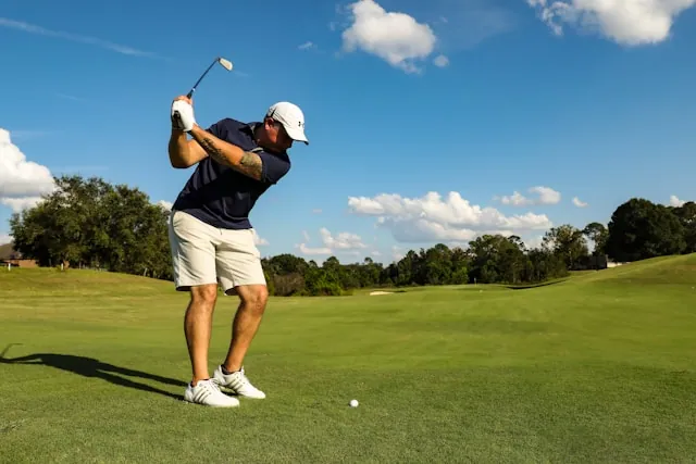 A man at the golf tee checking his phone